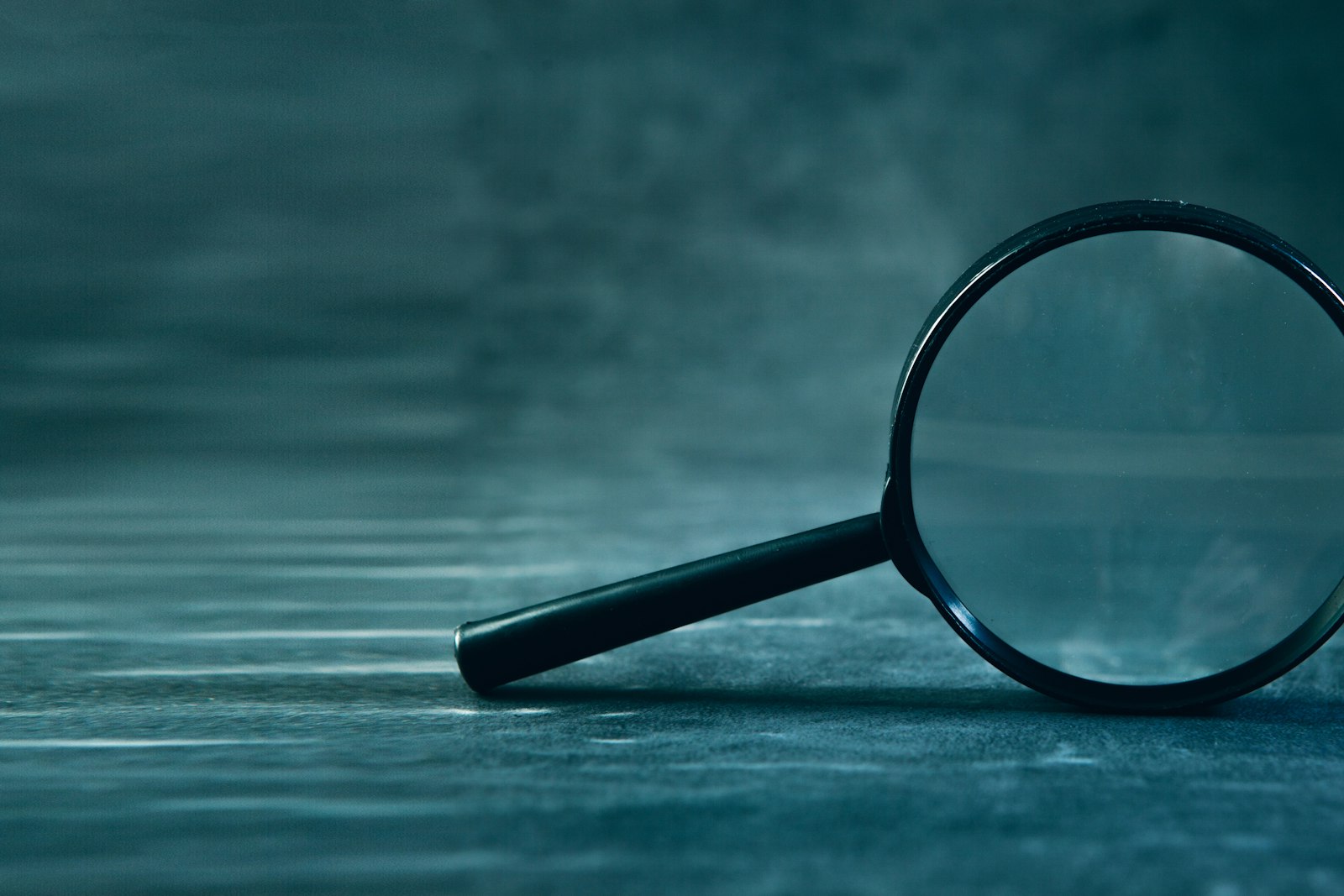 A magnifying glass resting on a dark surface